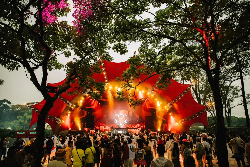 Palco do Tomorrowland Brasil 2024 no meio da natureza exuberante do Parque Maeda, iluminado por luzes vibrantes enquanto o público se diverte.