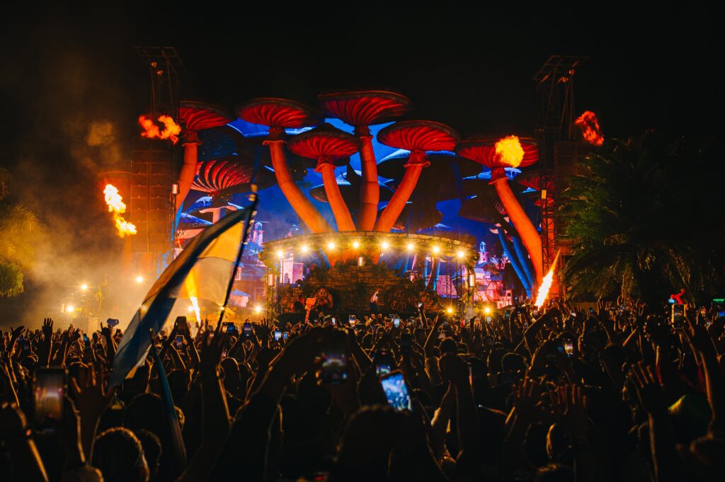 Palco iluminado do Tomorrowland Brasil 2024 com cogumelos gigantes e efeitos pirotécnicos.