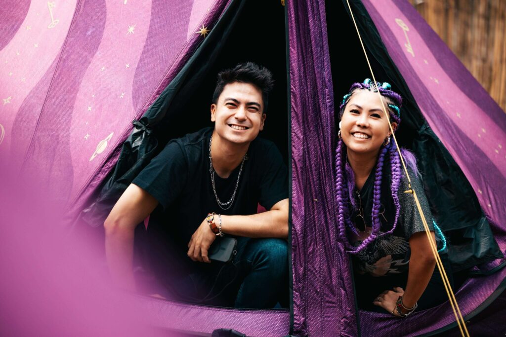 Dois jovens sorrindo na entrada de uma barraca personalizada no DreamVille durante o Tomorrowland Brasil 2025