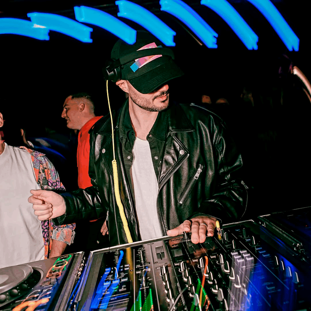 Kenzo (ITA) se apresentando em um clube com iluminação neon durante a turnê de divulgação do single “Again”, lançado pela Adesso Music.