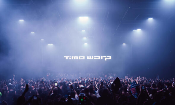 Multidão imersa em luzes e fumaça durante o festival Time Warp 2025 no Brooklyn Storehouse, Nova York