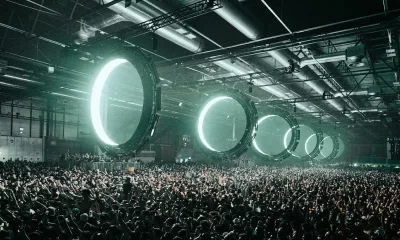 Multidão intensa no Outworld de Klangkuenstler em ambiente industrial, com luzes circulares futuristas e atmosfera de techno cru e imersivo.